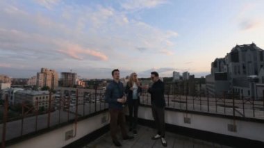 İnsanlar konuşmak ve çatıda bir ofis binası yaz akşamları içme