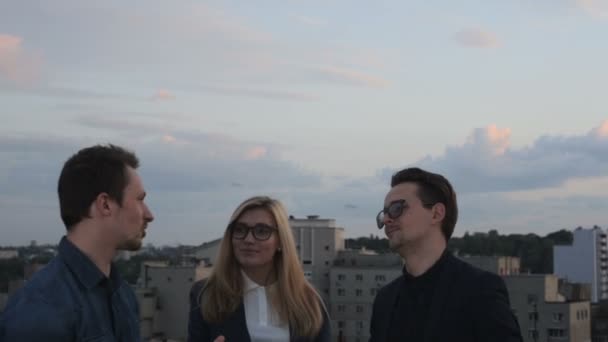 Люди разговаривают и пьют на крыше офисного здания в летний вечер — стоковое видео