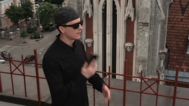 Людина в чорному/телефонувала на даху будівлі біля католицького собору fa — стокове відео
