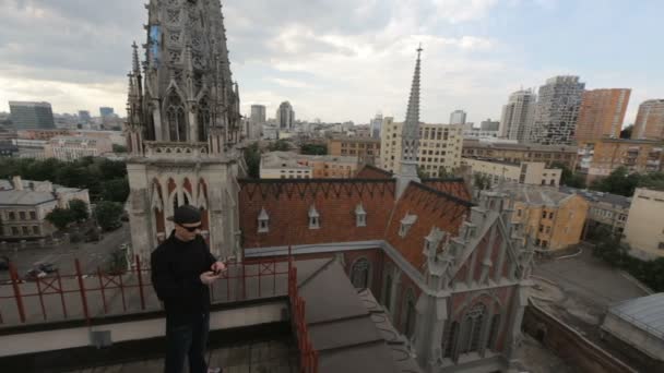 Homme en noir parlant au téléphone sur le toit de l'immeuble près de la cathédrale catholique fa — Video