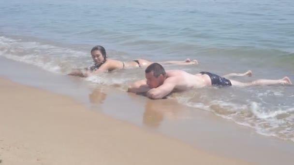 Ragazzo e ragazza sdraiati in mare nella linea di surf — Video Stock