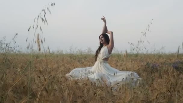 Mädchen Brünette im weißen Kleid auf einem Weizenfeld — Stockvideo