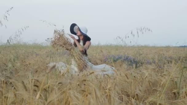 Menina morena em vestido branco e um chapéu no campo de trigo — Vídeo de Stock