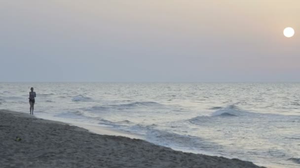 Chica trotando por la mañana a lo largo de la línea de surf de la playa de mar en verano — Vídeos de Stock