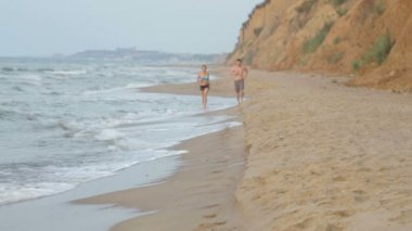 Sabah kız ve adam deniz plaj sörf hattı boyunca yaz aylarında koşu