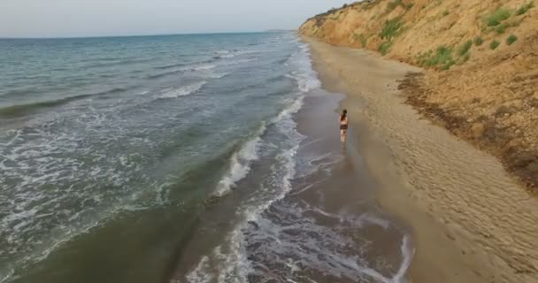 Chica trotando por la mañana a lo largo de la línea de surf de la playa de mar en verano — Vídeo de stock
