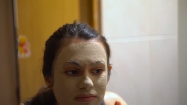 Menina com máscara cosmética no espelho no banheiro — Vídeo de Stock