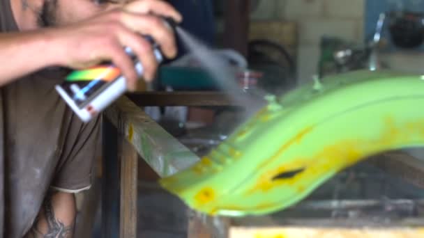 Homem com tatuagens colorir os detalhes da moto na garagem — Vídeo de Stock