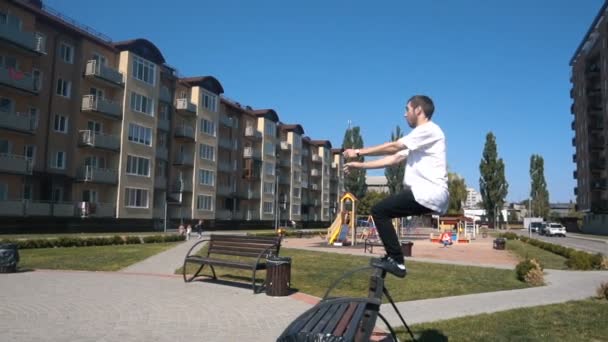 Ung man hoppar Vänd tillbaka från bänk på gatan — Stockvideo