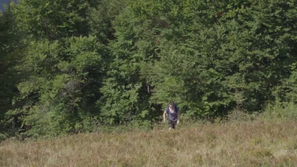 Joven con una mochila sube a la cima de la montaña — Vídeos de Stock