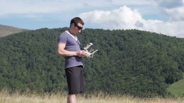 Молодой человек использует дрон в горах — стоковое видео