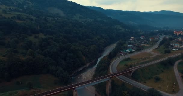 Железнодорожный мост через реку и горную дорогу — стоковое видео
