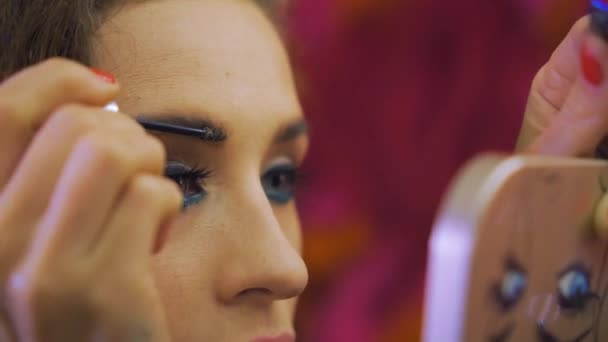 Beautiful woman dyes her eyebrows with a pocket mirror — Stock Video