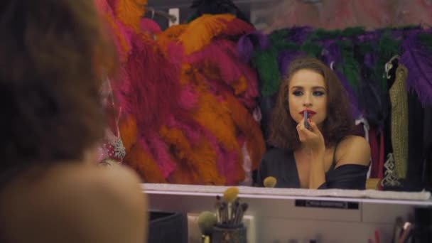 Schauspielerin schöne Mädchen bemalt Lippen mit rotem Lippenstift vor einem Spiegel in einer Garderobe, Make-up — Stockvideo