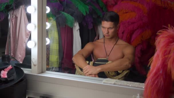 Männlicher Tänzer mit nacktem Oberkörper richtet seine Schultern vor dem Spiegel und bereitet sich auf die Show vor — Stockvideo