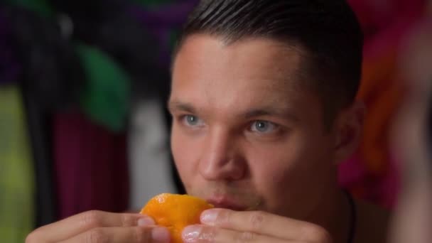 Jeune homme mange avidement orange — Video
