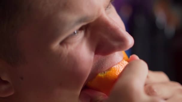 Jeune homme affamé mange avidement orange — Video