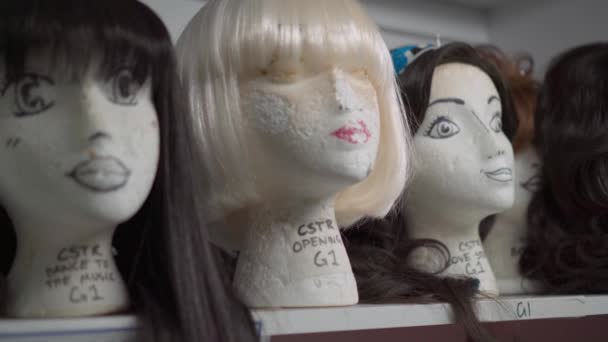 Женские манекены с париками на полках в гримерке — стоковое видео