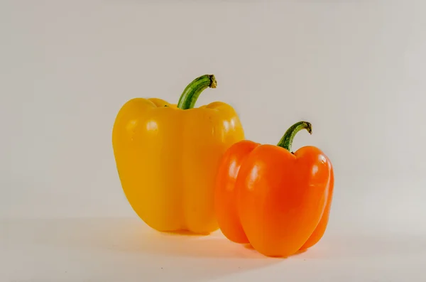 Turuncu ve sarı dolmalık biber beyaz arka plan üzerinde bir arada