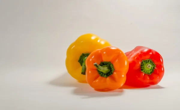 Beyaz arka plan üzerinde renkli kırmızı, turuncu ve sarı biber