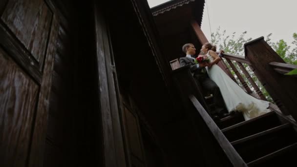 Lunas de miel de pie en las escaleras de una antigua casa de madera — Vídeos de Stock