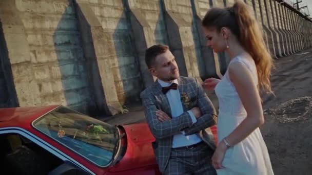 Novomanželé na pozadí přehrady a červené auto — Stock video