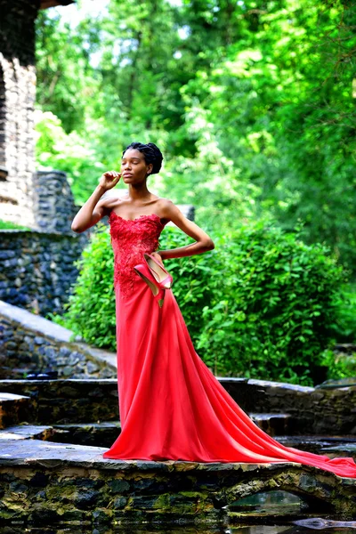 African American girl in a red dress with red shoes in hand