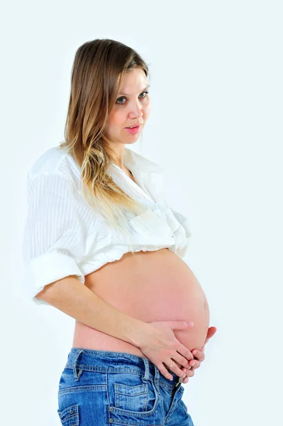 Dziewczyny w ciąży jest pozowanie z gołym brzuchem na białym tle — Zdjęcie stockowe