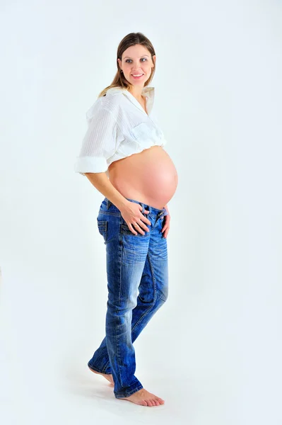 Beyaz arka plan üzerinde poz ve gülümseyen hamile kız — Stok fotoğraf
