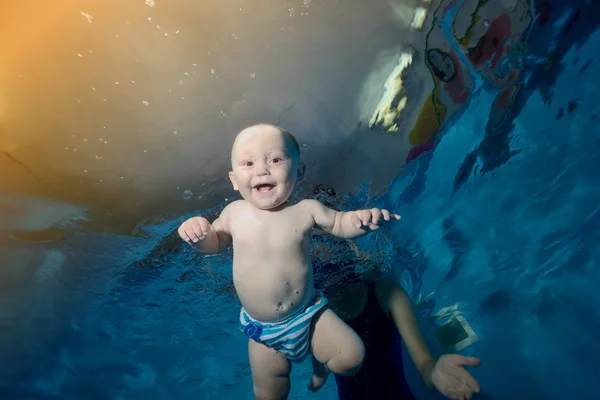 Feliz bebé nada bajo el agua en la piscina y se ríe — Foto de Stock