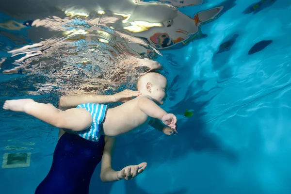 Petit garçon apprenant à nager dans la piscine, la mère soutient l'enfant et l'aide — Photo