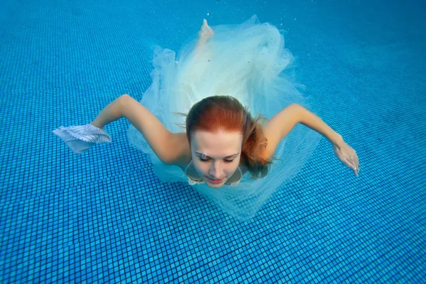 Panna Młoda pływa pod wodą w sukni ślubnej biały na niebieskim tle — Zdjęcie stockowe