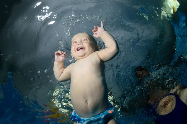 Bébé heureux nage sous l'eau dans la piscine avec une bouche ouverte, est heureux et rit. Gros plan — Photo