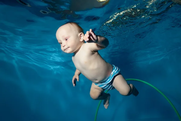 Un petit garçon apprend à nager sous l'eau dans la piscine. Portrait. Vue du bas — Photo
