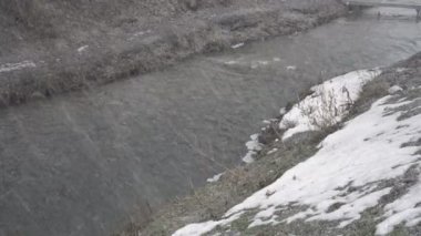 Şiddetli kar fırtınası ve hızlı bir nehrin üzerindeki dondurucu yağmur. Kötü hava. Kavram. 4K