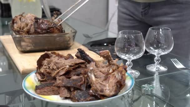 A man cuts and lays out pieces of hot roast duck on a plate. In the foreground are beautiful glass glasses. Still life. Close up. Shallow depth of field. 4K — Stock Video