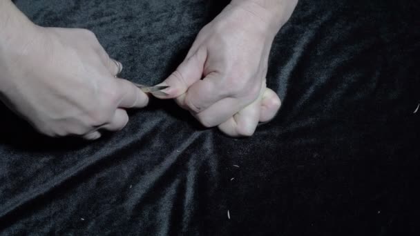 Взрослый парень стрижет себе ногти металлическими ножницами на чёрном бархатном фоне. Закрывай. Вид с вершины. Концепция. 4K — стоковое видео