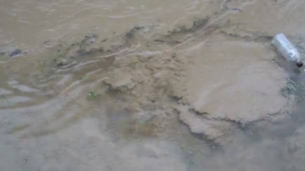 Durante a chuva, o lixo de plástico flutua na superfície de um rio lamacento. Conceito. Poluição ambiental. A vista de cima. 4K — Vídeo de Stock