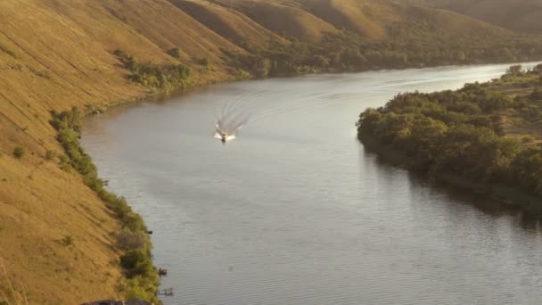 На закате по извилистой реке мчится белая моторная лодка. Вид с воздуха. Красивый пейзаж. 4K — стоковое видео