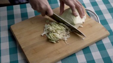 Bir kadın mutfaktaki ahşap bir tahtada taze bir lahana dilimliyor. Sağlıklı beslenme kavramı. Kapatın. Yukarıdan görünüşü