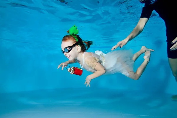 Una hermosa chica en un vestido blanco está nadando bajo el agua en la piscina. En las manos de una linterna. Decoraciones navideñas en la cabeza.Lección de afeitado. Estilo de vida saludable. Orientación horizontal — Foto de Stock