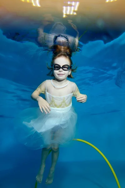 Foto de una niña bajo el agua en una piscina infantil. El bebé aprende a bucear. Clases de natación con un niño. Estilo de vida saludable. Orientación vertical — Foto de Stock