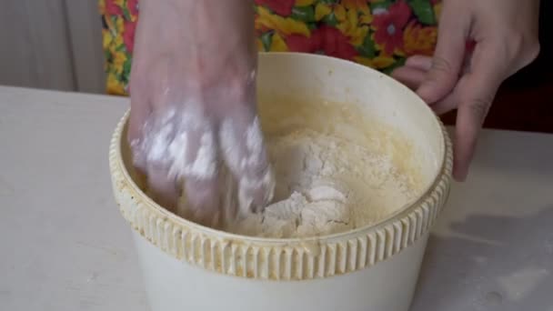 Primer plano, manos femeninas amasando masa en un tazón redondo en la cocina de la casa, sobre una mesa de madera blanca. El concepto de hacer pan. Primer plano. La vista desde arriba. Sin rostro. 4K — Vídeo de stock