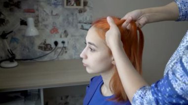 Bir kadın saçını ve örgülerini düşünceli kızıl saçlı bir kızın kafasına yapıyor. Kavram. Bir kadın portresi. Yan görüş. Yakın plan. 4K