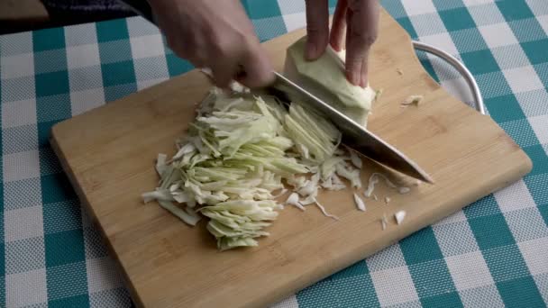 Primer plano de las manos de las mujeres rebanando la col blanca con un cuchillo grande en una tabla de madera en la cocina. El concepto de alimentación saludable. Sin rostro. La vista desde arriba. 4K — Vídeo de stock