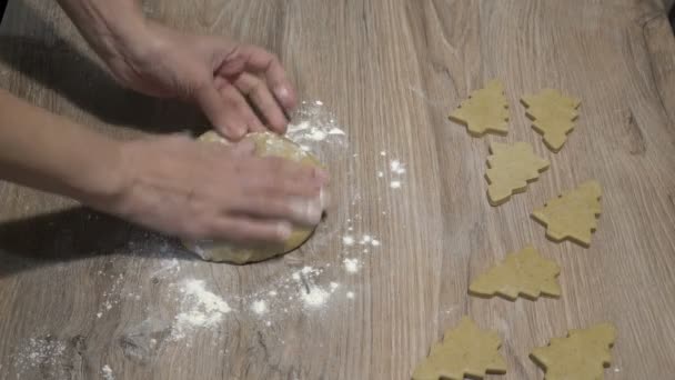 Uma mulher rola um pedaço de massa amarela em uma mesa de madeira com um rolo. Ela prepara biscoitos festivos na forma de uma árvore de Natal. Conceito. Close-up. A vista de cima. Sem rosto. 4K — Vídeo de Stock