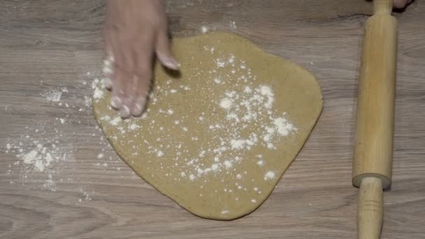 Žena dělá doma pizzu. Zploští kus žlutého těsta na dřevěném stole válečkem. Koncept vaření. Detailní záběr. Pohled shora. Bez tváře. 4K — Stock video