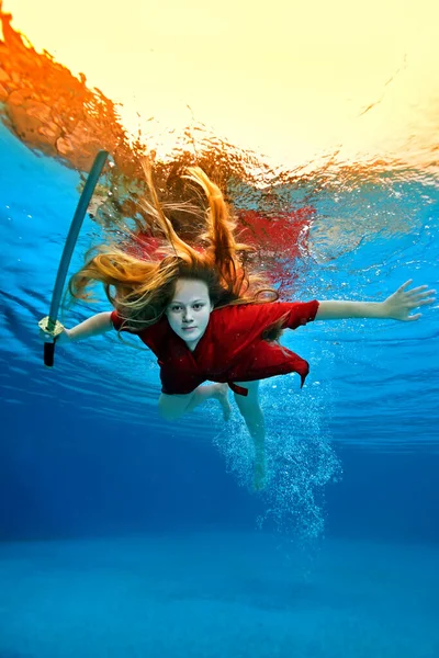 一个穿着红色和服的邪恶女孩一边看着摄像机一边在水里游泳，一边挥舞着武士刀。她的头发在水里飘扬.创意射击。概念。女性肖像. — 图库照片