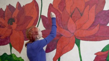 Genç bir kız yaratıcılıkla meşgul. Odasının duvarına güzel çiçekler çizer. Yakın plan. Yatay görüş. 4K