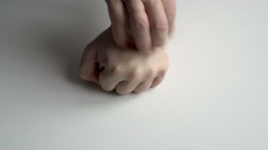 Deri iltihabı ve sedef hastalığı olan bir adamın yakın çekimi. Hasta bir elde beyaz bir arka planda yatan bir adam bir yarayı çizer. Üst Manzara. Yüzsüz. Uzayı kopyala 4K